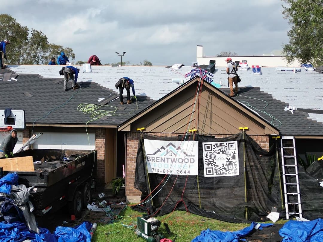 Roofing professionals install shingles on a home, showcasing Brentwood Roofing banner.