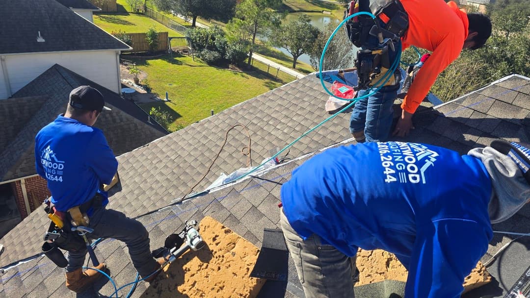 Roof repair crew working on a residential roof with tools and safety gear.