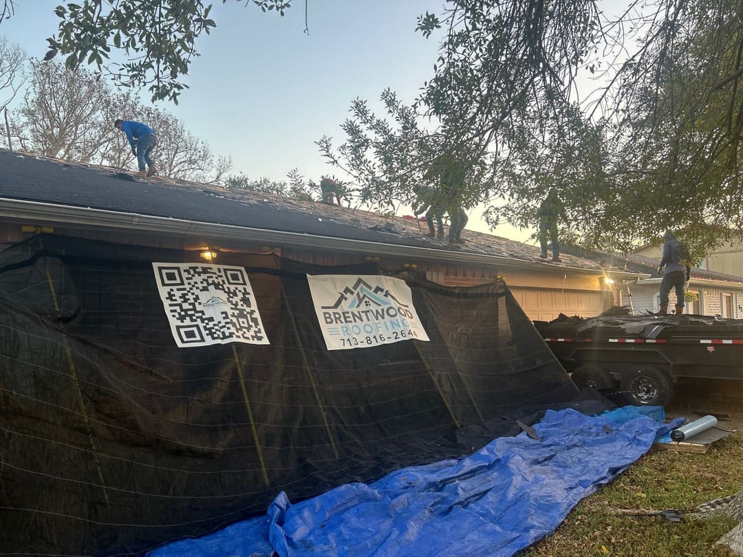 Roofing crew working on a residential home, Brentwood Roofing sign prominently displayed.