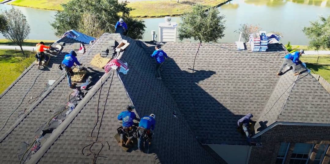 Roofing crew working on a home with tools and materials in a sunny outdoor setting.